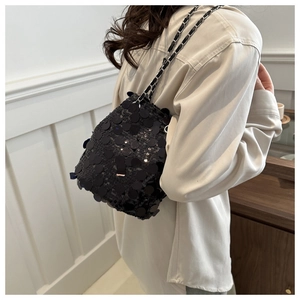 Detail shot of shimmering black sequins and woven metal chain on the bucket bag