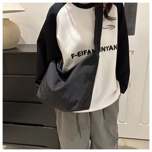 Detailed close-up of large black pleated canvas tote bag worn by a model in casual style