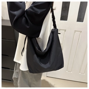 Detail of black crescent tote bag with woven handle and large capacity texture