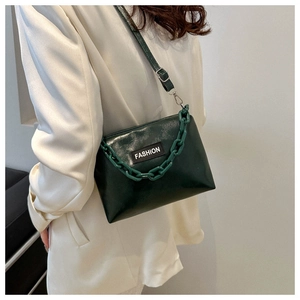 Detailansicht der dunkelgrünen Umhängetasche mit Acrylkette und FASHION-Label am Modell
