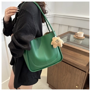 Dettaglio della borsa tote in pelle verde con ciondolo a orsetto e doppi spallacci