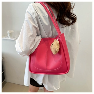 Borsa tote rosa con ciondolo a forma di orsetto indossata da una modella su sfondo bianco