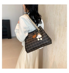 Detail of brown plaid tote bag with woven rope handles and white pompom charm