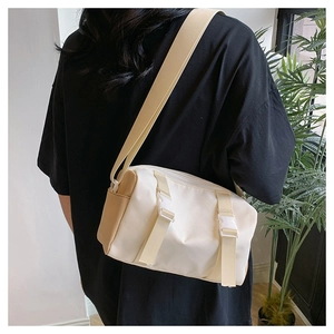 Detail of a beige and khaki nylon crossbody bag with dual buckles on a model