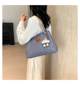 Detail of blue checkerboard tote bag with woven rope handles and plush charm