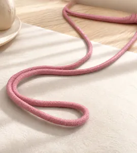 Detail van een roze gevlochten schouderband op een mini schelpvormige strandtas