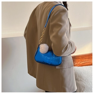 Detail van glanzend blauwe halve maan tas met slangenpatroon, goudkleurige ketting