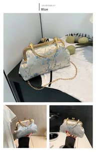 Détails de broderie florale bleue sur sac coquillage vintage avec fermoir doré