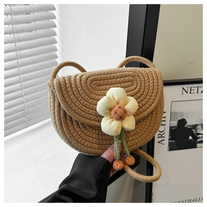 Detalle del mini bolso de paja con gran flor de tela decorativa y correa de cordón trenzado