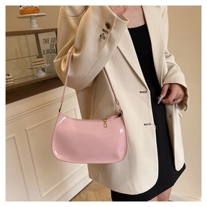 Sac hobo en cuir verni rose porté avec un costume beige dans un café