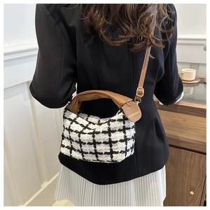 Detail van zwart-witte tweed geruite tas met bruine lederen handvaten en schouderband