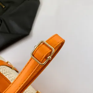 Λεπτομέρεια του ρυθμιζόμενου δερμάτινου ιμάντα ώμου με χρυσή αγκράφα σε ψάθινη τσάντα