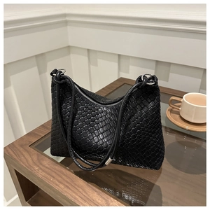 Dettaglio della trama in pelle intrecciata nera di una borsa hobo con dettagli in metallo