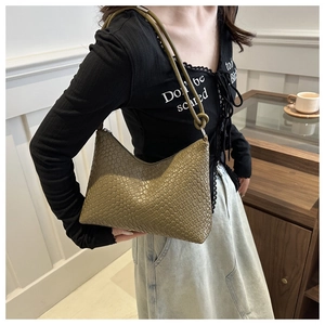 Dettaglio della trama intrecciata borsa a spalla verde oliva indossata da una modella