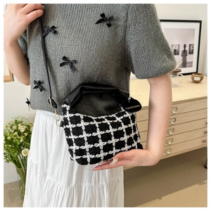 Dettaglio della borsa in tweed a scacchi con manico in pelle nera ed etichetta moda