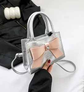 Detail of silver handbag featuring a large pink bow and heart-shaped rhinestone buckle