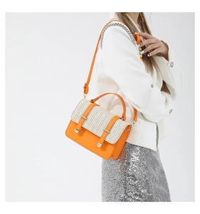 Detail der gewebten Strohklappe und orangefarbenen Lederstruktur einer Damenhandtasche