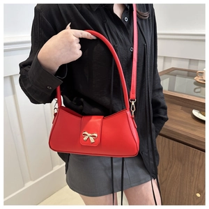 Détail du sac sous l'aisselle en cuir rouge avec boucle dorée en forme de nœud