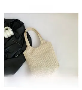 Détail du sac cabas beige tressé montrant la texture fine et la bandoulière intégrée
