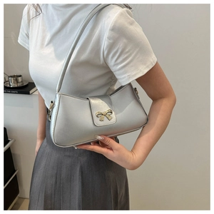 Détail du sac baguette argenté avec fermoir nœud doré et bandoulière fixe pour femme