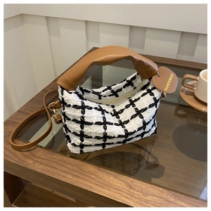 Dettaglio borsa in tweed bianco e nero con manico in pelle marrone e fibbie dorate