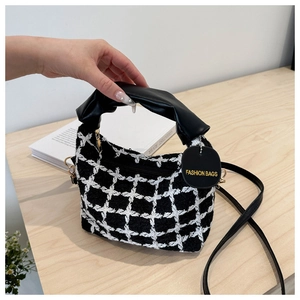 Dettaglio borsa a quadri bianchi e neri in tweed con manico in pelle e zip metallica