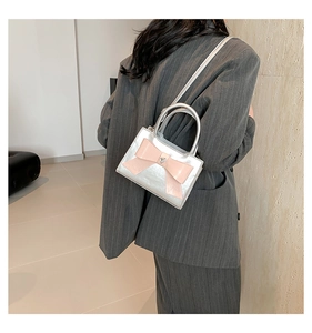 Detail van zilveren mini crossbody tas met roze strik en hartvormig metalen ornament