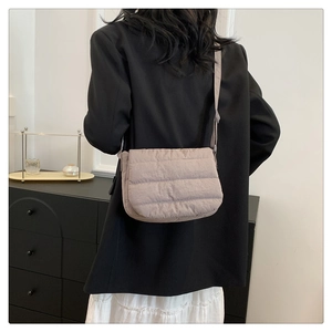 Vista posterior de un bolso bandolera acolchado marrón claro sobre blazer negro y falda