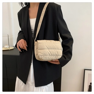 Vista lateral del bolso bandolera de nailon acolchado beige con textura suave y asa
