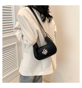 Détail du sac à bandoulière noir en forme de croissant avec boucle fleurie argentée