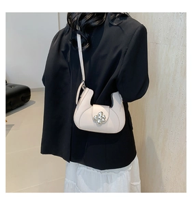 Détail du sac demi-lune en cuir beige avec un fermoir floral en métal argenté