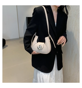 Vue latérale du sac croissant en cuir crème avec boucle fleur argentée sur le modèle