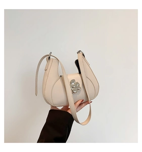 Détail du sac croissant crème avec fermoir fleur argentée et similicuir texturé