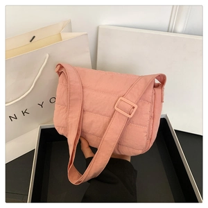 Detalle de bolso bandolera rosa acolchado con textura suave y correa de hombro ajustable