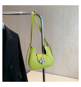 Détail du sac à bandoulière demi-lune en cuir vert néon avec fermoir fleuri sur un cintre