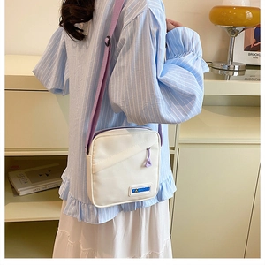 Vue lifestyle d'un sac bandoulière en toile blanche avec bandoulière violette et patch