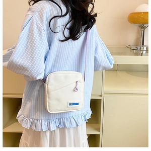 Vue arrière d'un sac bandoulière en toile blanche avec bretelles violettes sur un mannequin