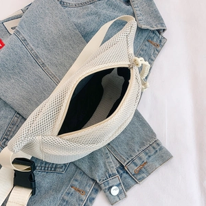 Detail of white mesh crossbody bag with durable buckle on a denim jacket background