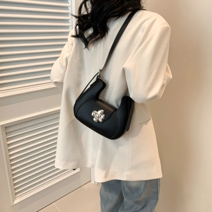 Sac demi-lune noir élégant avec fermoir fleur argentée porté par un mannequin