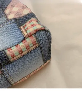 Macro detail of patchwork denim and checkered fabric stitching on large tote bag