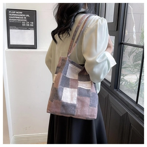 Patchwork tote bag with geometric color blocks worn as a shoulder bag by a model