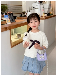 Detail of girl wearing white knitted top and denim skirt with purple mini handbag
