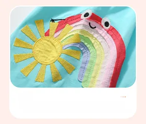 Close-up of rainbow and sun embroidery on blue cotton dress for girls