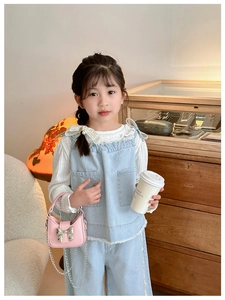 Detail of blue denim ruffled top and white pearl collar shirt on a young girl