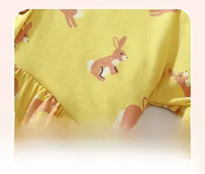 Détail du tissu en coton jaune avec imprimé lapin rose et finitions à volants