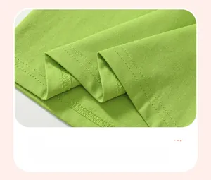 Détail macro de l'ourlet à double surpiqûre sur un t-shirt d'été en coton vert pour enfant