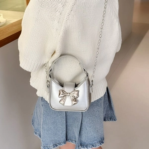 Silver metallic mini crossbody bag with bow decoration for girls shown on model