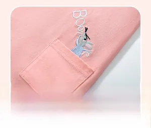 Dettaglio di un abito rosa in cotone con tasca, ricamo a topo e scritta Boo