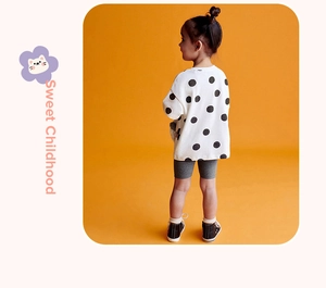Detail of girls polka dot sweatshirt and grey leggings set against orange background