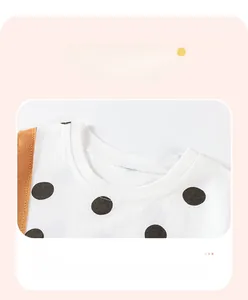 Detail of white cotton girls' t-shirt featuring black polka dots and ribbed neckline